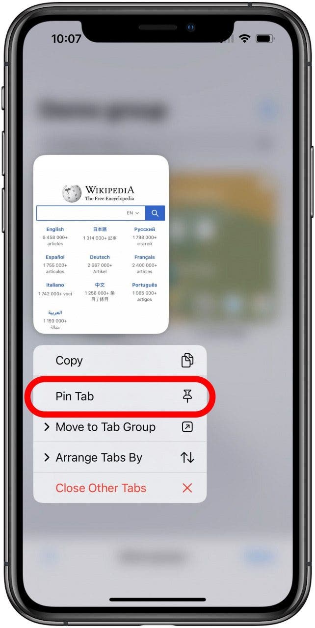 Safari-App mit dem Registerkartenbildschirm für eine Registerkartengruppe, die im Hintergrund verschwommen ist, und einer einzelnen Registerkarte, die mit dem darunter geöffneten Menü für langes Drücken sichtbar ist. Die Option Pin Tab ist im Menü markiert.