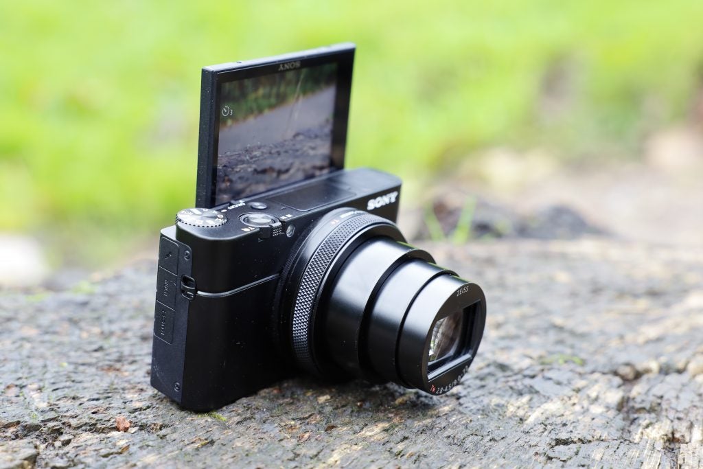 Linksschräge Ansicht einer schwarzen Sony RX100 VII-Kamera, die auf dem Boden steht und deren hinterer Bildschirm umgedreht ist, sodass er nach vorne zeigt