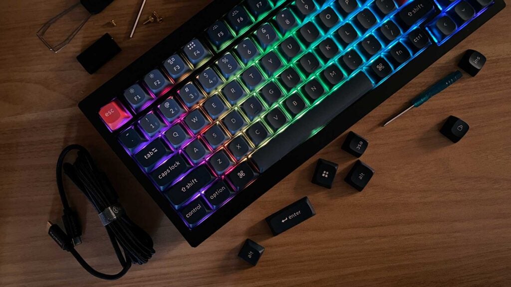 Eine dunkle Aufnahme des Keychron V1 Max, der seine RGB-Beleuchtung und das mitgelieferte Zubehör zeigt.