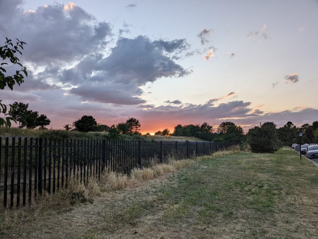 Foto von grünem Gras, schwarzen Toren und einem Sonnenuntergang, aufgenommen mit dem Pixel Fold