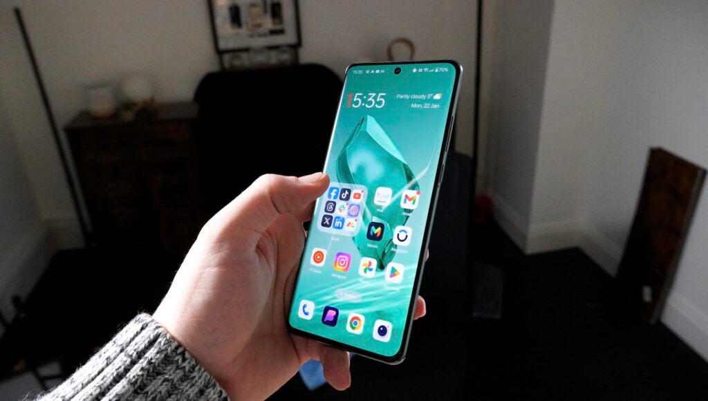 Hand hält ein OnePlus-Smartphone, auf dessen Bildschirm Apps angezeigt werden.
