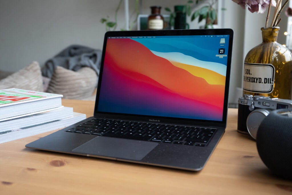 Vista frontal en ángulo derecho de un Macbook Air M1 gris plateado de pie sobre una mesa de madera
