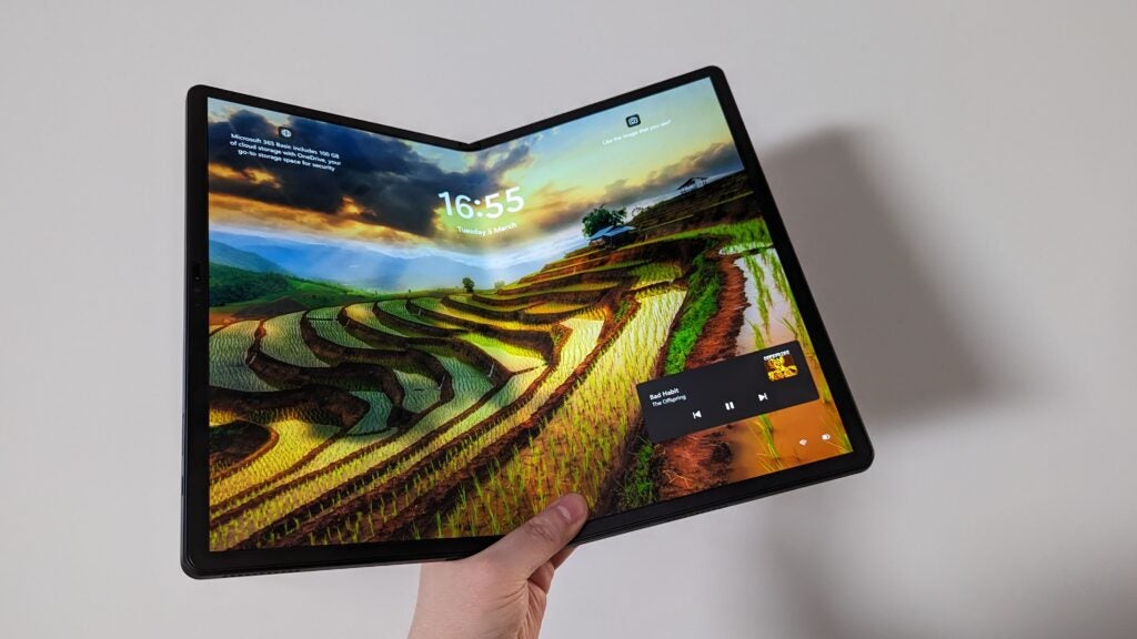 Mano sosteniendo Lenovo ThinkPad X1 Fold con papel tapiz horizontal.