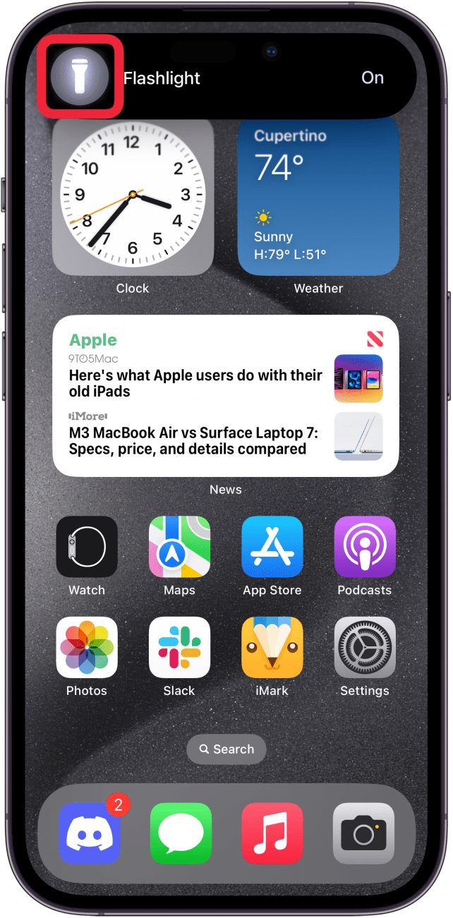 pantalla de inicio del iPhone que muestra una isla dinámica expandida con un ícono de linterna y un cuadro rojo alrededor del ícono de linterna