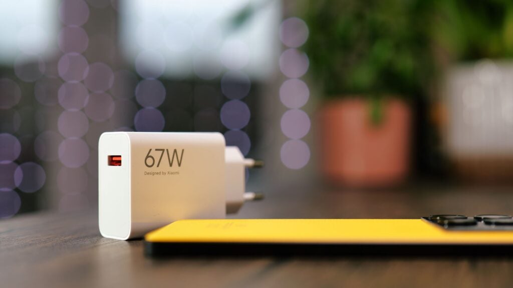 Cargador Xiaomi de 67W sobre una mesa con fondo bokeh.