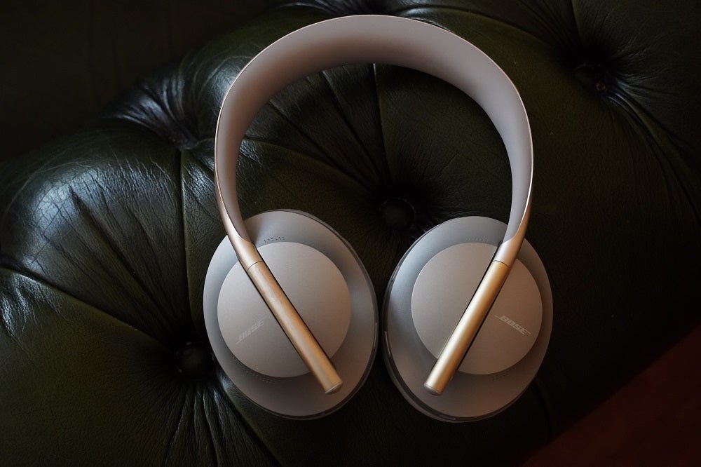 Casques Bose de couleur crème reposant sur un canapé noir doux