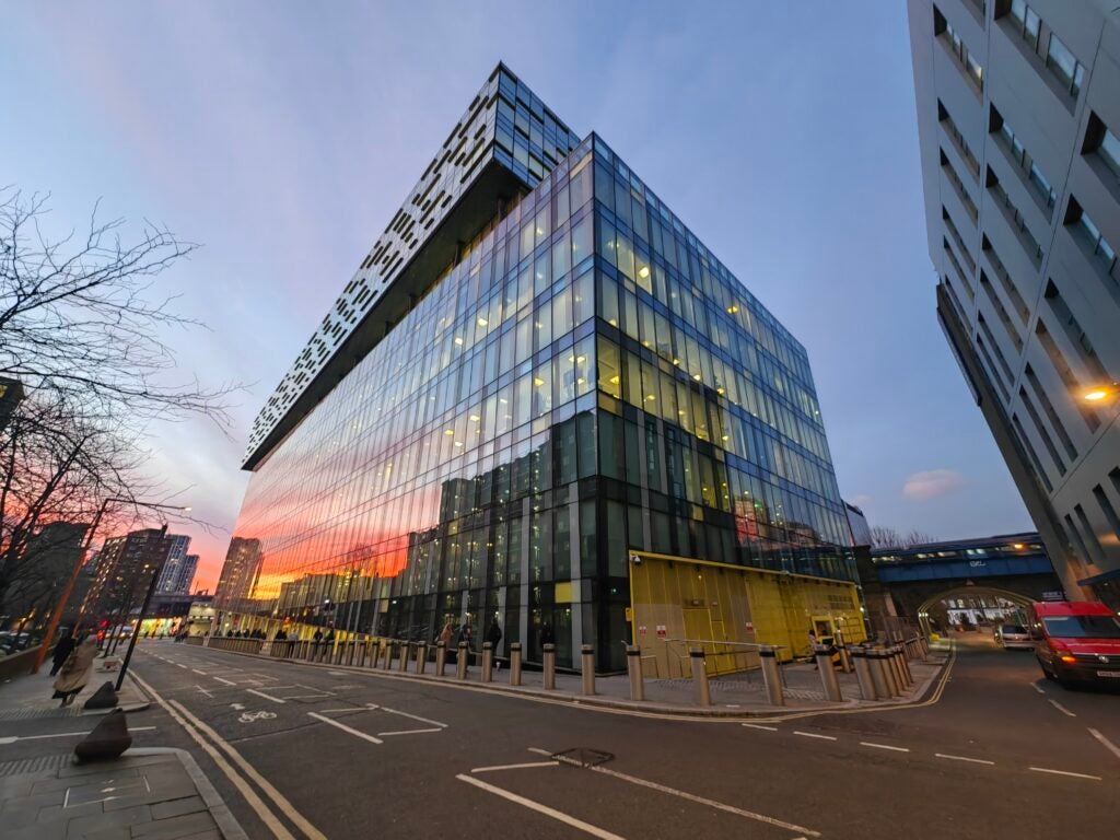 Image ultra-large du coucher de soleil réfléchi sur un bâtiment en verre prise par le Huawei P50 Pocket