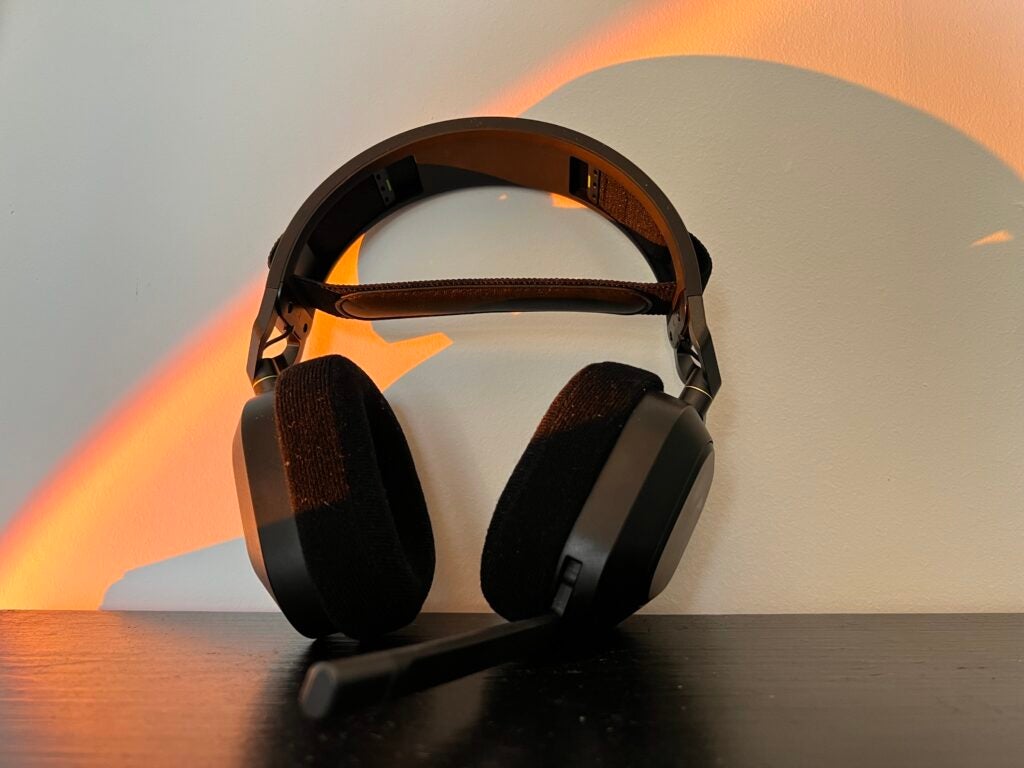 Le casque Corsair HS80 RGB appuyé contre un mur sur un bureau noir