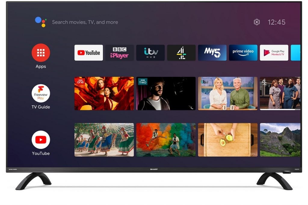 Sharp 50DL3KA stock photoSharp 50DL4KA TV avec support affichant les applications, le guide TV et la section youtube avec un bouton de réglage en haut à gauche et la barre de recherche de l'assistant Google en haut à droite