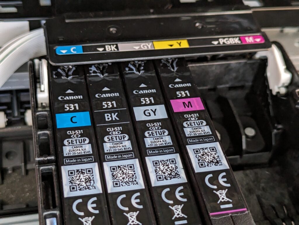 Prise de vue des cartouches d'encre, montrant la cartouche magenta partiellement insérée dans la fente jaune